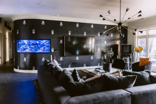 This edgy, rock-inspired wall features a striking built-in saltwater fish tank, blending rugged textures with the calming