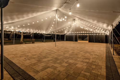 Magical event space under a softly lit tent with a charming brick floor, ready to create unforgettable moments for any