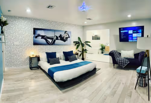 Massive primary bedroom with a king size bed, lounge chair and big screen tv. at Stylish Fun Modern Near the strip